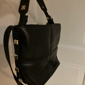 Väska med nitar - Säljer den här fina väskan ifrån Zara⭐️Den är svart med ett långt band och ett litet kortare med nitar på. Superfin och den är lagom stor. Med dragkedja💓