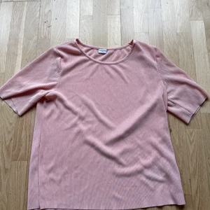 Rosa t-shirt ifrån Jaqueline deYoung - En rosa t-shirt i silkesmaterial ifrån Jaqueline deYoung i storlek s. T-shirten är lite ribbad och ärmarna något längre. Längd är 57 cm. Fler bilder kan fås och den kan skickas 