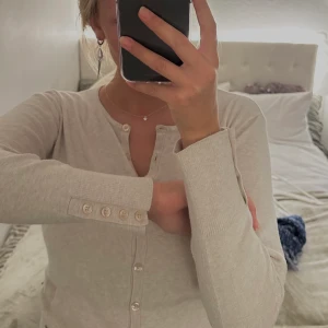 Beiga kofta - Beige kofta med knappar. Fick detalj på vänstra sidan. Perfekt att ha helt knäppt som en tröja eller öppen över en top/klänning.