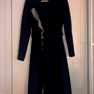 Marinblå kappa från 2NDDAY - Marinblå kappa med grå volangdetaljer. Storlek 38. Köpt 2020 för 1800. Använd ett fåtal gånger och är som ny i väldigt bra skick. Skickar gärna fler bilder om så önskas. 