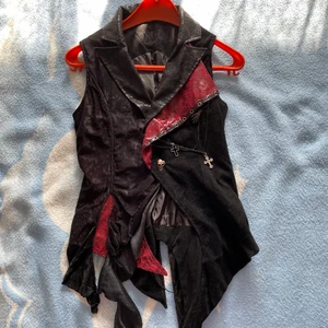 Cool väst från PunkRave - Cool väst från Punk Rave clothing.  M-XXL På lappen står det XXL men snörningen bak gör att man kan dra ihop den till en M. Knappen har gått sönder och försvunnit för en evighet sedan men jag har sytt på en liten dödskalle som knapp  