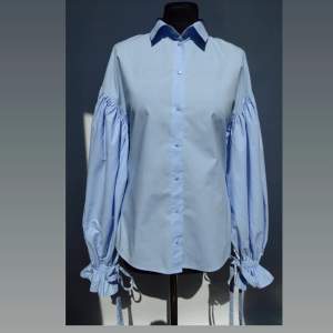 Blå bomullsskjorta från Monki med ballongärmar som avslutas med resår och en knytbar rosett. Knappt använd så i mycket bra skick (extraknapp medföljer). Storlek M. Kan skickas/upphämtas 