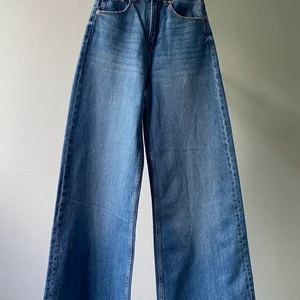 Blåa vida jeans - Nyinköpta blåa, vida jeans från Bershka med hög midja. Storlek 32/XXS men skulle säga att de snarare är storlek 34/XS. Avklippta nedtill. Säljer då de är lite för tighta för mig. Kan mötas upp eller frakta mot betalning.
