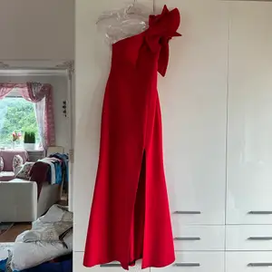 Röd balklänning/långklänning, använd en gång. I nytt skick, med slits, one shoulder. Förkortad så den passar någon som är runt 1,60. 