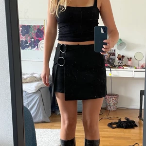 Svart kjol - Svart kjol från bershka med silver detaljer. Kjolen har endast använts en gång då jag sällan bär kjol och har därför inga defekter. Hör gärna av dig vid frågor:)  Tryck ej på köp direkt! 