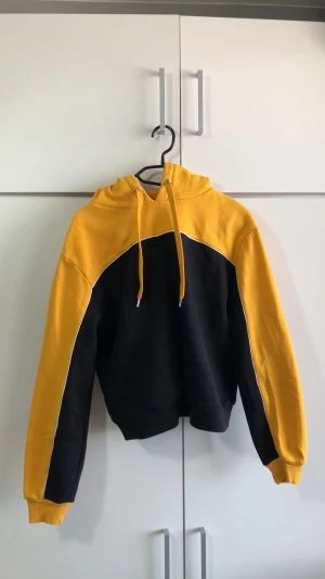 Svart och gul hoodie - Jätte fin gul och svart hoodie som passar på en som en smäck. Den har en väldigt unik design vilket gör den jätte fin. Köpt för 200 kr🤍