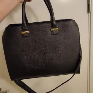 Stor svart väska med handtag eller axelrem. Guld detaljer. Rymmer allt från träningskläder till datorer. Den är använd men väldigt fint skick. 