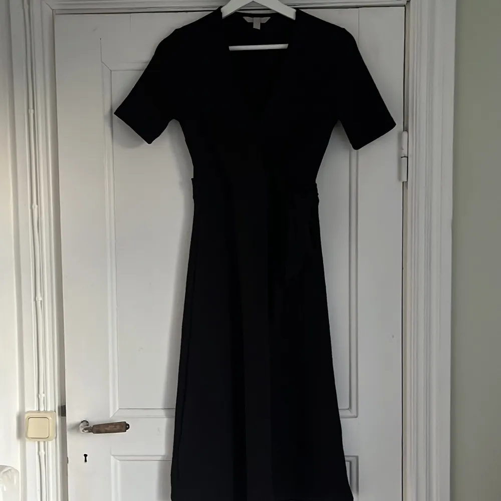 Jätte fin svart omlottklänning! Där klänningen går ihop är den fastsydd så den åker inte upp om man kan oroa sig för det! Använd en gång, med andra ord väldigt bra skick. Lite större i storleken så passar helt klart en S. . Klänningar.