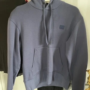 Acne hoodie - Supersnygg acne hoodie i en mörkblå färg. Liten svag fläck upp till men syns bara i starkt ljus annars som ny. Använd några gånger. Oversized på mig som vanligtvis är XS. Köptes för 2100kr. Spårbar frakt på 66kr tillkommer