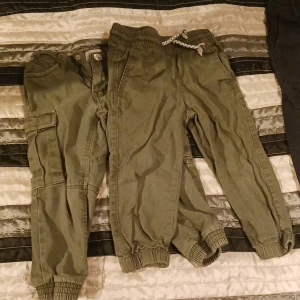 2 byxor barn - 2 mörkgröna byxor 1 med snörning i storlek 92, 1 med knapp i storlek 90.