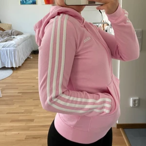 Adidas hoodie - Ljusrosa Adidashoodie i barnstrl L som jag använt ett fåtal gånger 💌 Den är i fint skick förutom en liten fläck på höger ficka (syns på sista bilden) ❤️‍🔥 Jag är 1,60 och bär vanligtviss strl XS-S för referens. Fraktas spårbart för 57 kr!
