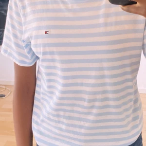 TOMMY HILFIGER T-SHIRT🎸⚡️ - PRISER ÄR 35kr+FRAKT  Blå/vit randig Tommy hilfiger t-shirt köpt i storlek 152-164 (som motsvarar storleken xs i kvinno storlek) den sitter lite thightare där uppe och sitter bra till vid midjan.  En väldigt fin sommar t-shirt som kan kläs på många sätt.🤍