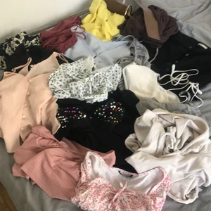 Kasse med kläder  - Säljer 18 kläderplagg med en massa blandade kläder. Bland annat är det två svarta kappppor i strl: 36/M, 3 mjukis shorts, 10 toppa/topp olika färger, blommiga, helfärgade, grå snygg body, en svart jeans kjol med knappar hela framsidan. Ett brunt midje skärp. Dessa kläder passar folk i S/M