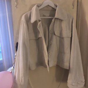 Vit beige kortare jacka från NLY - Så snygg vit/beige jacka i manchester tyg. Snygga stora knappar och lite vidare ärmar. Kortare modell. strl 40 men passar snyggt lite oversize på mindre också.