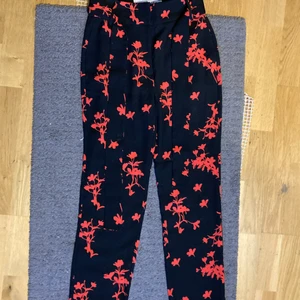 Kostymbyxor  - Kostymbyxor med röda blommor på. Jättefin passform! (Tyg skärp ingår) Bra skick! Köparen står för frakten.