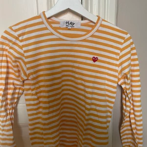 Comme des garçons långärmad randig - Säljer min superfina lånärgamde t-shirt från comme des garçons. Den är randig i orange och vitt. I bra skick men har ett litet hål precis vid lappen. I storlek small, säljer den då den blivit för liten. 
