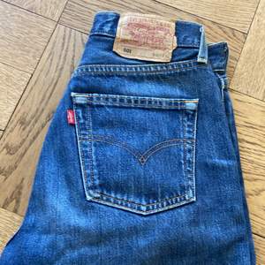 Ett par lågmidjade levis jeans köpta från en secondhandbutik. Mycket bra skick. Väldigt långa så tidigare ägare vikte upp benen (se bild 3). Passar bra för en person som vanligtvis har 24-26 i midja och har relativt långa ben. Jeansen är en manlig modell men jag skulle säga att vem som helst kan ha på sig dem. 