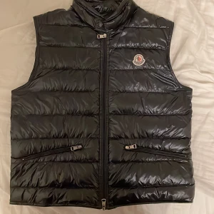 Moncler down gui gilet väst - Storlek 2 - Marinblå färg (nästintill svart) Finns litet skrapmärke under högerficka (syns ej vid använding) Äkthetsbevis finns - har även påse till västen Säljer för att den är för liten Tveka ej på att kontakta mig för mer information/bilder