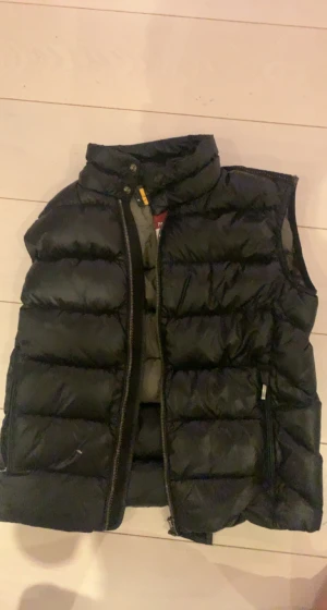 Parajumper väst barnstorlek Y-S / 150-165  - Parajumper väst Använd men grymt skick Ett litet hål på yttersta lagret men det går att fixa och det läcker inte ut någon fodring Tillgänglig i Stockholm Nypris 3300