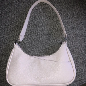 DonDonna handväska - Det är en relativt liten handväska, väldigt ljuslila.  Har tre små fack i väskan, syns på bild. Aldrig använd, mått 26x17x6