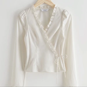 omlottblus med knyt- och volangdetaljer - superfin krämvit omlottblus med knyt- och volangdetaljer från & other stories! så fin till middagar, fest, events, etc. 