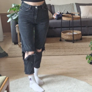 Svarta högmidjade jeans - Svarta jeans med hål över knäna från monki. Modellen "Taiki high waist ballon leg". Lite stretchiga, men inte mycket. Storlek 27 (s). Kan mäta midja, höft, och insida ben om det skulle önskas, samt skicka fler bilder. Använda, men inte slitna!