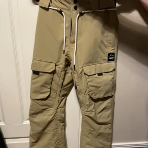 Dope skidbyxor - Skidbyxor från dope, beiga. Toppskick! Flera fickor både fram och bak. Modellen heter Dope Iconic W. Köpte för 1599kr