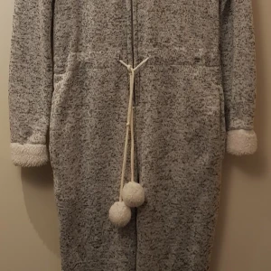 Mysdress - Grå/vit mysdress med luva, snörbollar, två fickor på sidorna i fint använd endast en gång skick. Storlek Xs Pris 100kr  Finns att hämta i Malmö