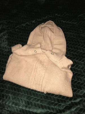 Stickad huvtröja - Stickad huvtröja (ej ull). Aldrig använd. Finns tillhörande snören som jag kan skicka med. Lössittande men något tajtare i ärmarna.