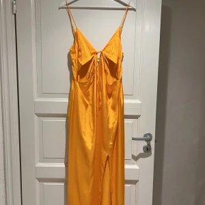 Orange sommarklänning - Jättesöt orange sommarklänning med slits! Aldrig använd, prislappen sitter kvar. Köparen står för frakt <3