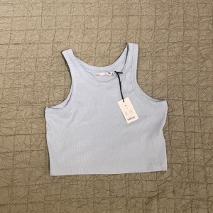 Linne från Lager157 - Ett ljusblått linne med brottartygg från Lager157. Aldrig använt med lappen kvar i storlek M. 