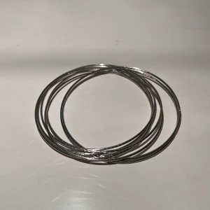 Armband i silvermetall - Armband i silvermetall. 7 tunna ringar som sitter ihop.  Ca 6 cm i diameter. Finns på Hägerstensåsen i Hägersten. 