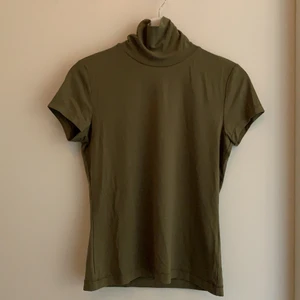 Kortärmad polotröja från Whyred - En supersnygg kortärmad polotröja i en khakigrön färg från märket Whyred. Är i mycket bra skick och oanvänd. Passform: tight. Storlek: S. 