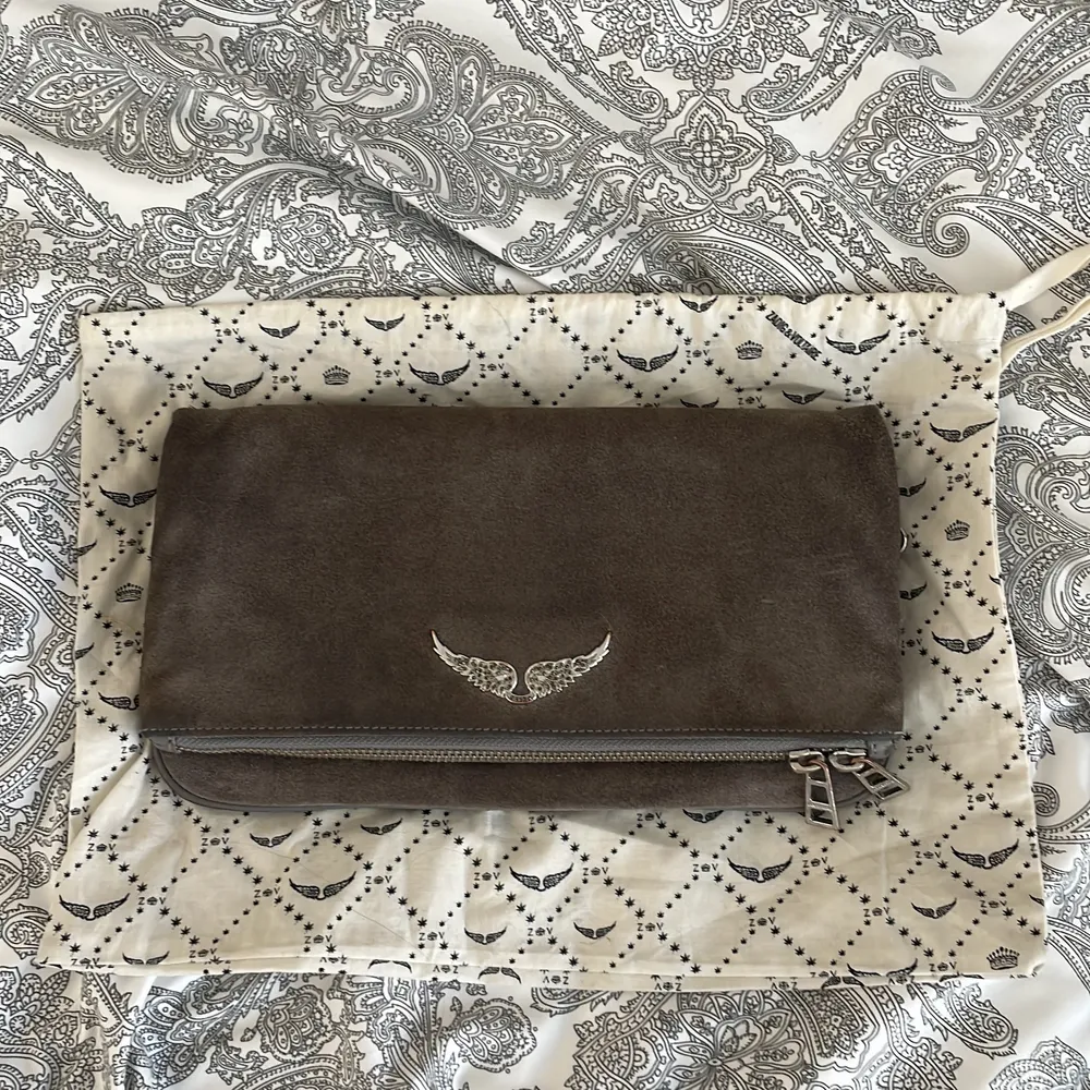 Zadig Voltaire Rock Clutch in gray suede and silver metal details. Bought in 2018 used several times but still in very good condition. Two straps one long and one shorter. 4 different compartments. Comes with dustbag.. Väskor.