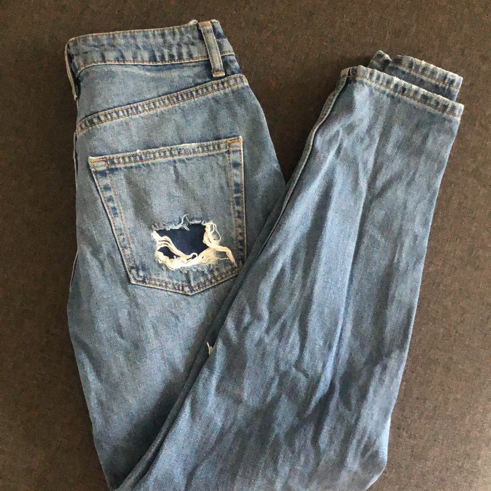 Blåa ”mom jeans” med hål i knäna och bak. . Jeans & Byxor.