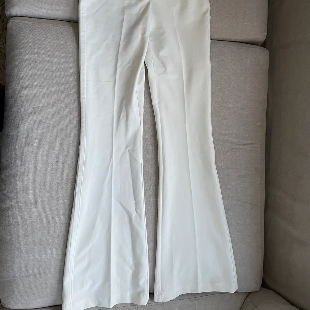 Vita bootcut kostymbyxor i stretchigt material och hög midja.  Använt men fint skick med någon synlig defekt på byxkanten då de är långa.. Jeans & Byxor.