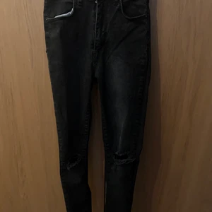 Svarta byxor  - Helt tajta och svarta jeans med hål i knäna