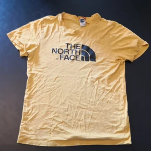 North Face T-shirt  - En gul och välanvänd t-shirt från The North face. Den har skrynklig krage och lite sliten svart logga på bröstet. 