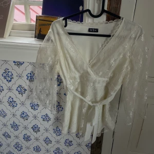 Tunika / blus - Superfin blus / tunika i en varm vit färg, kan knytas fram eller bak. Köptes secondhand och är knappt använd. Säljer då den ej kommer till användning!
