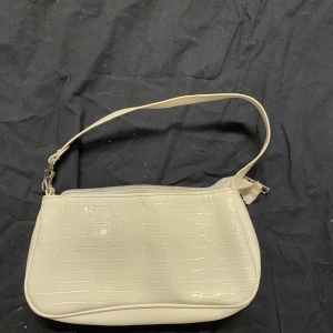 Liten vit handväska - Fin liten vit handväska Ganska kort band så går tyvärr inte att ha över axeln men ändå väldigt fin.