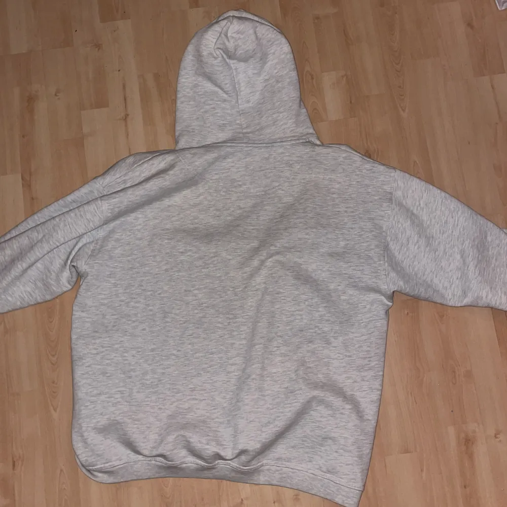 Champions gråa hoodie med mörkblå text och guldfärg runt om. Oversize hoodie med smala snören. Hoodiens luva har haft en gul nyans länge som finns kvar efter en vanlig tvätt. Vanlig oversize på de som är under storleken XXL.. Hoodies.