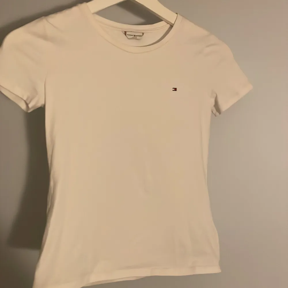 En Äkta vit Tommy Hilfiger t-shirt, helt oandvänd, inga fläckar, äkta märke och i storlek xxs men funkar för XS🤍säljer denna eftersom att jag rensar min garderob och har helt enkelt inte plats för den, orginal pris är 499 kr men säljer för 189 kr 🤍. T-shirts.