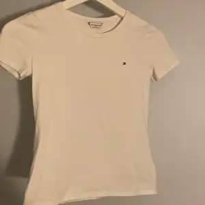 En Äkta vit Tommy Hilfiger t-shirt, helt oandvänd, inga fläckar, äkta märke och i storlek xxs men funkar för XS🤍säljer denna eftersom att jag rensar min garderob och har helt enkelt inte plats för den, orginal pris är 499 kr men säljer för 189 kr 🤍