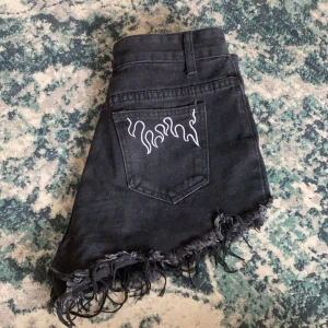 Söta jeansshorts - Coola jeansshorts med broderade detaljer på båda bakfickorna. Bra skick förutom att dragkedjan är lite slö (funkar som den ska) och att knappen är lite lös (funkar som den ska). 