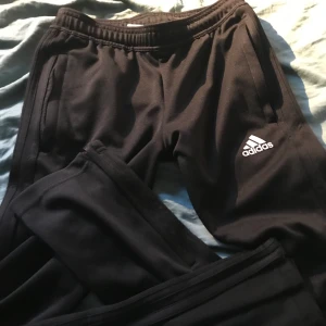 Adidas träningsbyxor - Adidas med svarta ränder o brodyr på vänster ben. Mycket fint skick.  Stl 152