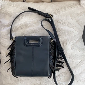 Maje väska  - Säljer min älskade maje väska som är ganska använd, som ni ser på bilderna är själva ”handtaget” ganska slitet på baksidan men inget som syns när man har på sig den, texten med ”maje” är också lite utsuddad men annars bra skick! Skriv för frågor!!!❤️