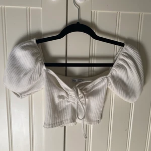 Vit croptop med knytdetalj och puffärm - Vit cropad topp från ZARA i storlek S. Knytdetalj i fram och puffärm.  Köpare står för frakt.  Hör av dig vid intresse!