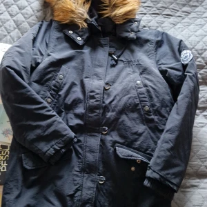 Jacka med luva - Jacka med luva. Storlek 160 Använd men i fint skick. En dold tryckknapp har lossnat på en utav fickorna men det är inget som påverkar jackans funktion.