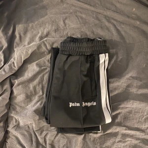 Palm Angels Track Pants - Tjena, säljer nu mina Palm Angels byxor. Typ 8/10 i cond imo, pga ett litet märke på vänster knä som knappt syns och bara syns ifrån vissa vinklar. Fler bilder kan lösas såklart. Storlek L  Bud: 2000kr Bin: 2250kr (SKRIV INNAN KÖP)