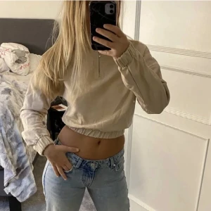 beige tjocktröja  - En beige tjocktröja med dragkedja som går upp lite i halsen. Lite kortare modell och den är knappt använd!